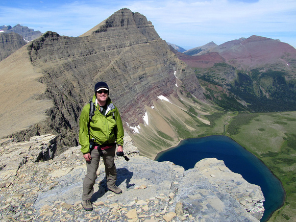 Rob poses next to a huge drop off above Kennedy Lake with Crowfeet Mountain directly above him.