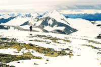 Mark walks across the plateau near the summit with Mount Baker dominating the scenery behind him.